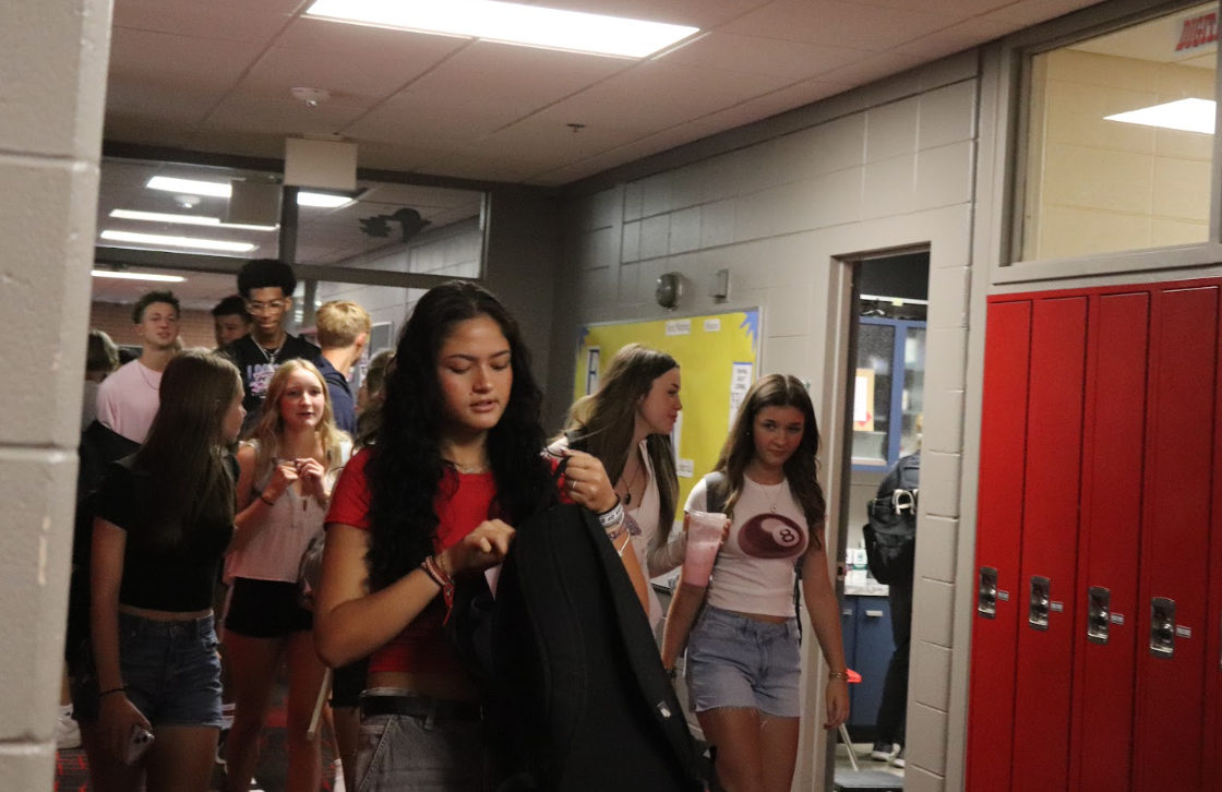 Students walk to their first class on the first day of school and talk to one another.